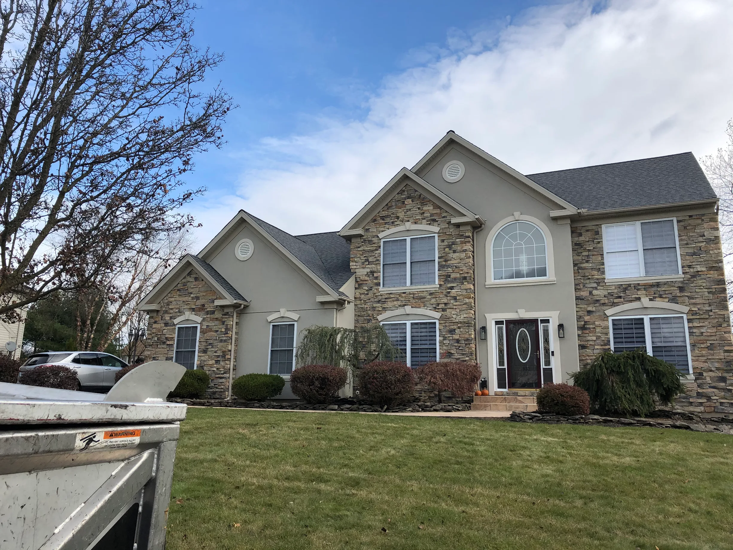 Stone Colonial House with Shingle Roof and Dumpster