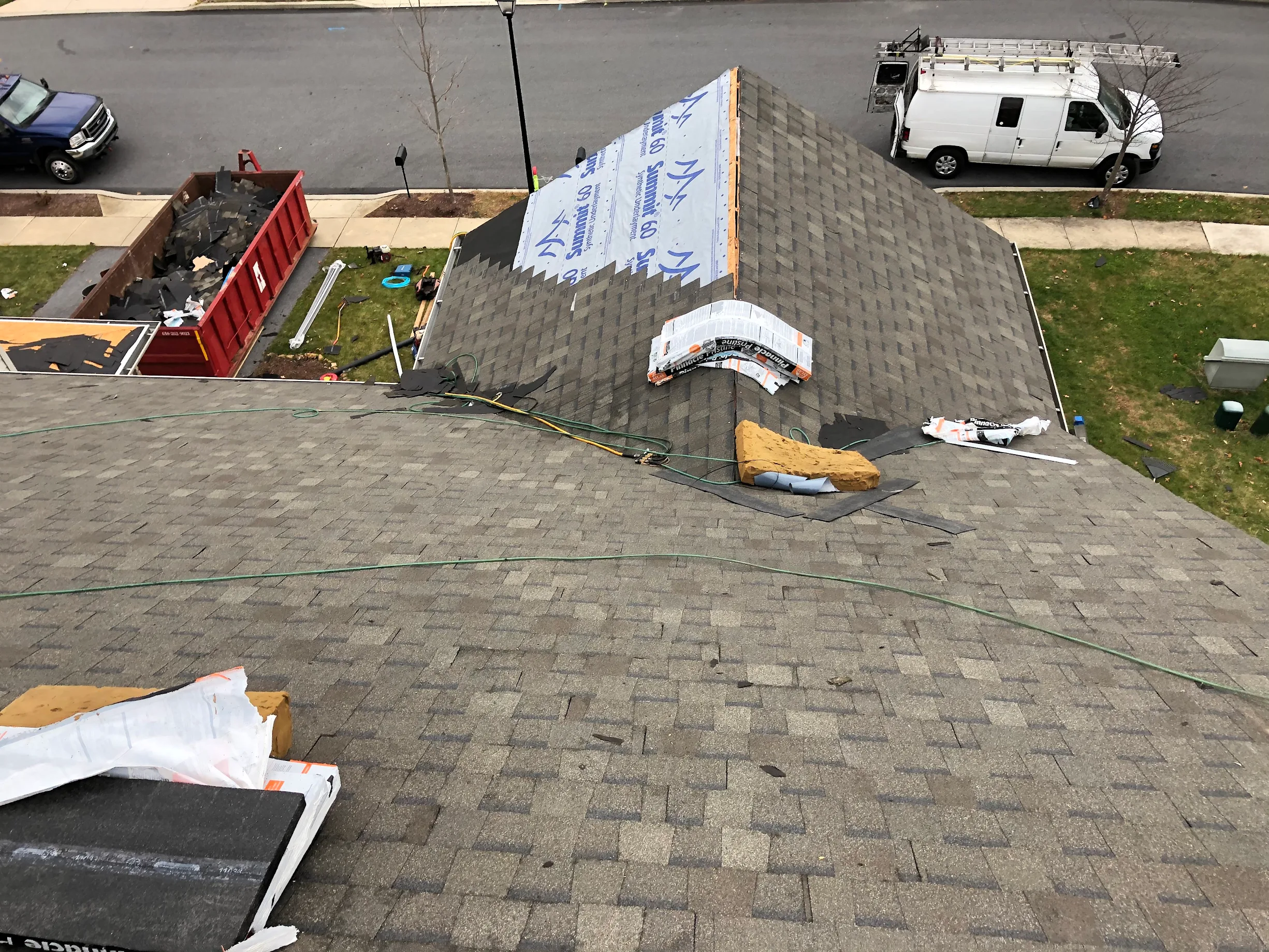 View from Rooftop Being Reshingled with view of work van, dumpster, and materials